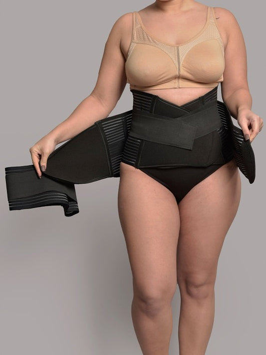 Woman modeling black 3-in-1 postnatal shapewear belt on neutral background