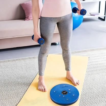 Woman using tummy twister abs exerciser and dumbbells on yoga mat in living room